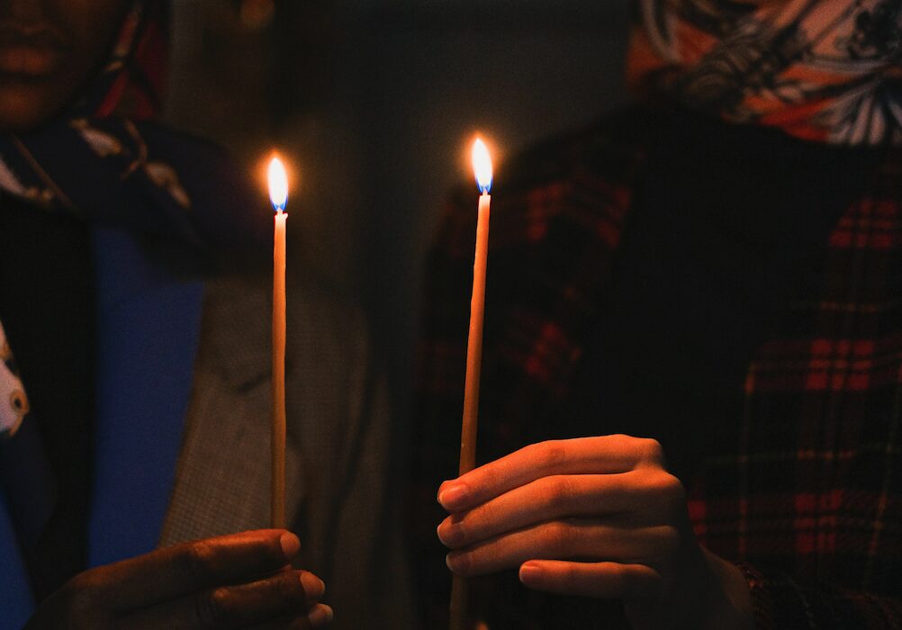 2 hands holding candles