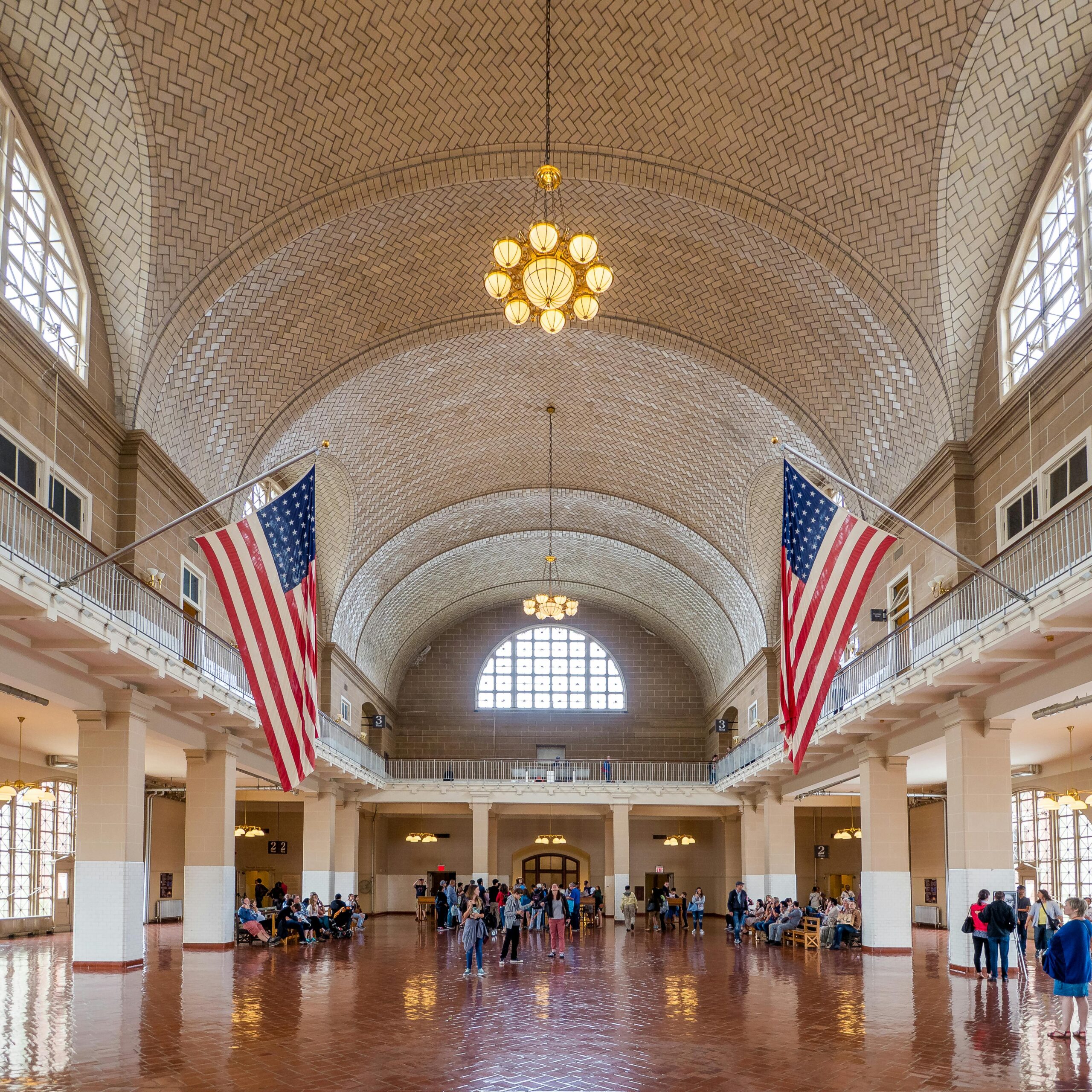 people in Ellis Island immigraiton museum with two american flags