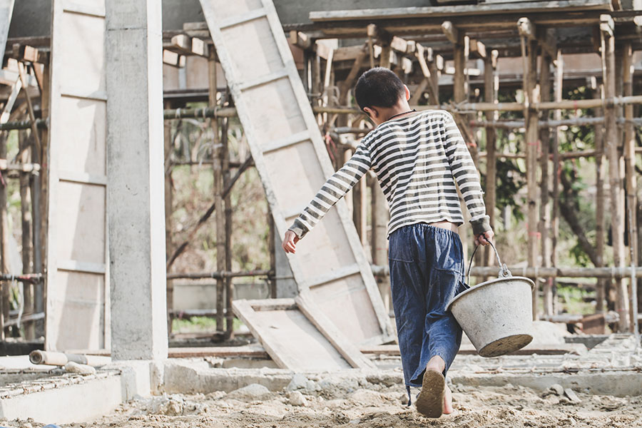 child carrying bucket on job site
