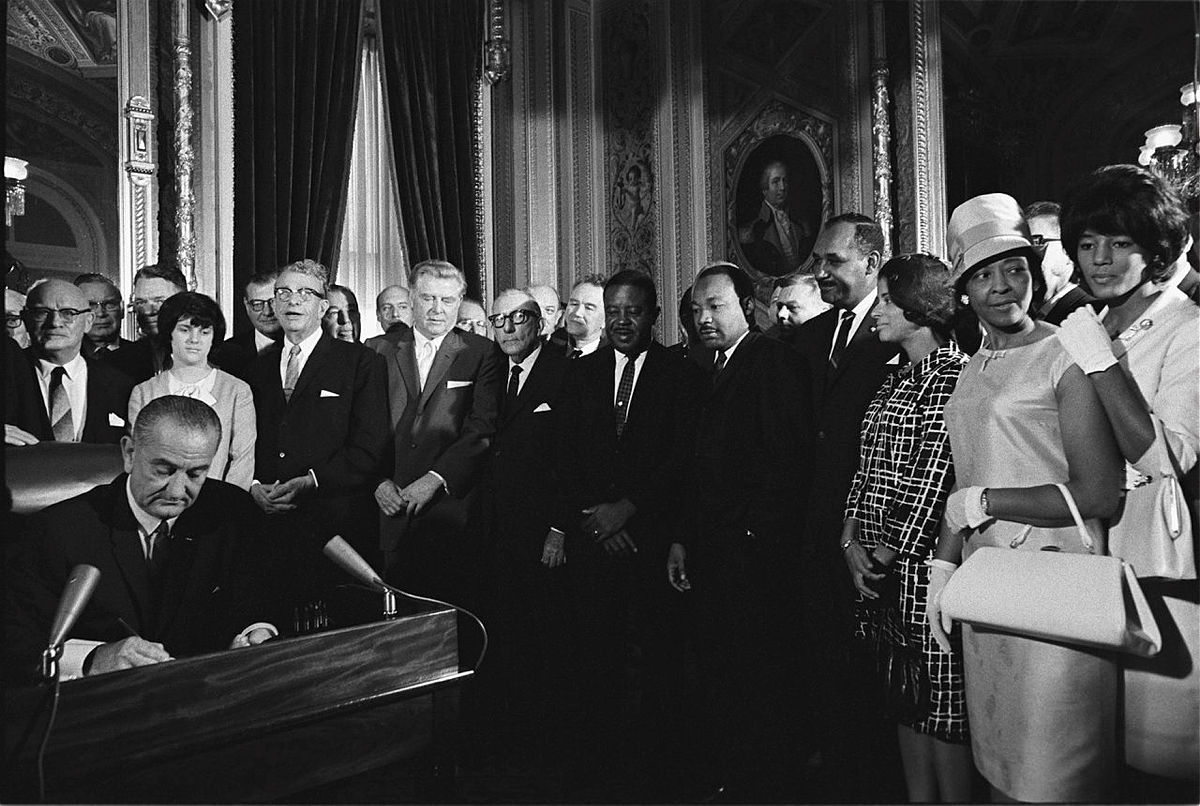 black and white photo of president johnson signing voting rights act with people behind him
