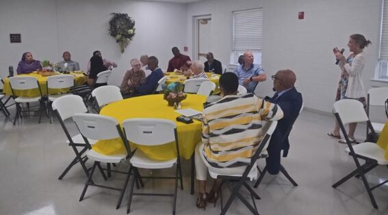 people seatd at tables listening to speaker