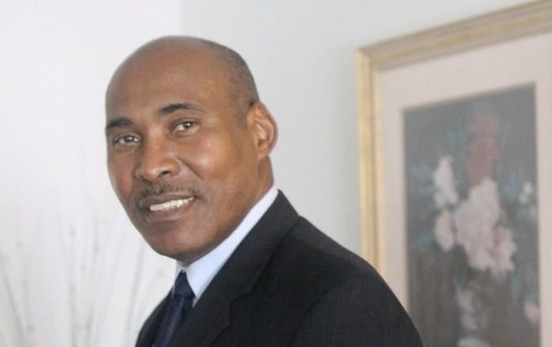 Man in black suit looks at camera
